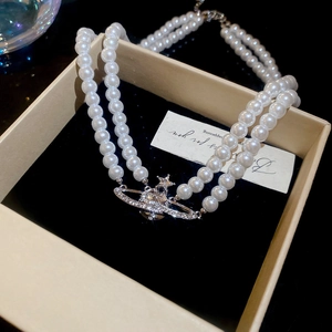 Detailed view of Saturn planet pendant with crystals on double-layer pearl necklace
