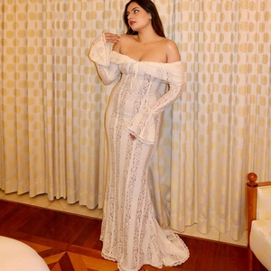 Dettaglio della trama in pizzo su un abito lungo beige con eleganti maniche a campana