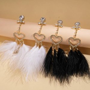 Detail of rhinestone heart earrings featuring elegant black and white feather tassels