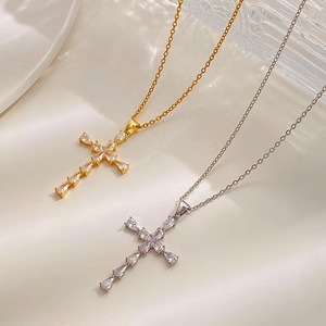 Close-up of gold and silver cross necklaces with sparkling zircon stones on glass