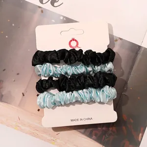 Close-up of four-piece satin scrunchies set in black and light blue on display card