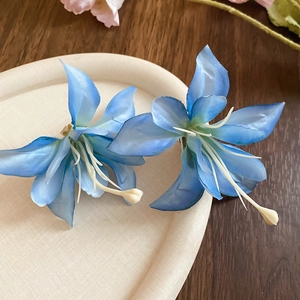 Detail of blue gradient lily hair clips with fabric petals on a wooden background