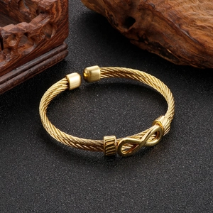 Detail of golden stainless steel wire rope bracelet with infinity symbol on black background