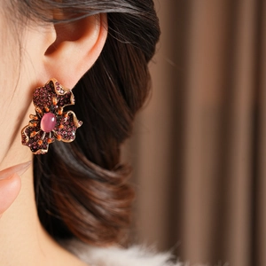 Détail d'une boucle d'oreille fleur en résine vintage avec cristaux violets
