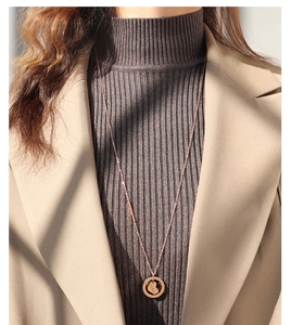 Dettaglio della collana con pendente a cuore in oro rosa e incisione Luck su maglione