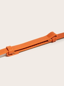 Close-up of orange Saffiano leather waist belt showing detailed stitching and texture