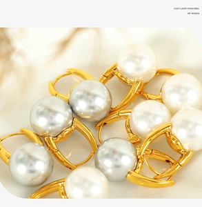 Detailed view of elegant white and grey pearls on high-quality golden hoop earrings