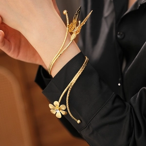 Detailed view of a gold-tone butterfly and flower cuff bracelet with sparkling rhinestones
