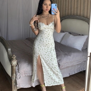 Detail of white midi dress with green floral print and a stylish side slit feature