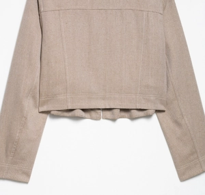 Detail van kaki visgraat twill stof textuur op een korte jas met strakke afgewerkte naden