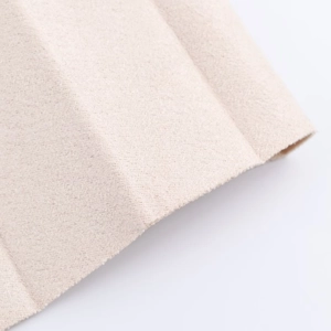 Détail macro du tissu plissé beige avec texture en daim doux et finition en tricot raffiné