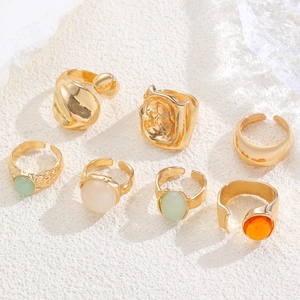 7-piece gold ring set with colorful gemstones and textured metal in retro minimalist style