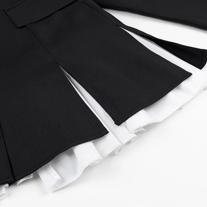 Detail of black dress hem showing white pleated lining and woven fabric texture