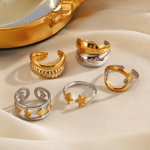 Set of gold and silver stainless steel rings with stars and heart designs on satin