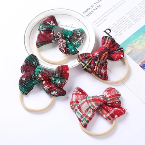 Close-up of four Christmas plaid baby headbands with snowflake patterns and soft nylon bands