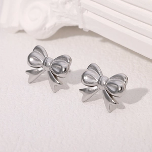 Elegant silver stainless steel bow knot stud earrings on a clean white textured background