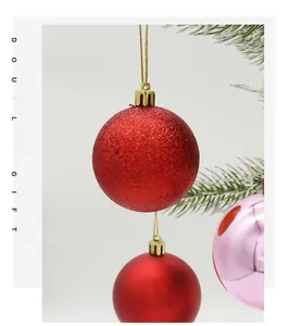 Close-up of red glitter Christmas ball ornament with golden hook on snowy pine branch