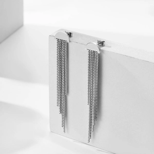 Minimalist silver stainless steel long tassel earrings on a geometric stone display