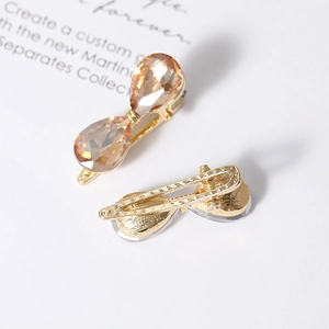 Elegant gold metal hair clip featuring champagne crystal bow design on a white card