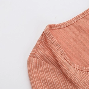 Dettaglio dello scollo a V in maglia arancione con cuciture rinforzate sulla spalla