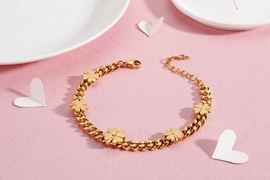 Detailed shot of golden four-leaf clover bracelet with zircon on white porcelain