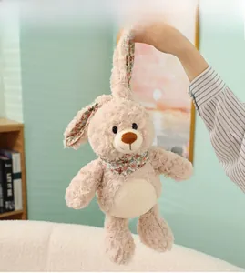 Detalle de una mano sosteniendo las orejas largas de un conejo de peluche rosa con flores