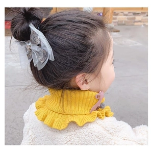 Detail of yellow knitted children's neck warmer with ruffle trim and button closure