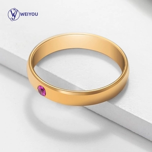 Detailed close-up of a minimalist gold ring with a round purple birthstone in a smooth setting