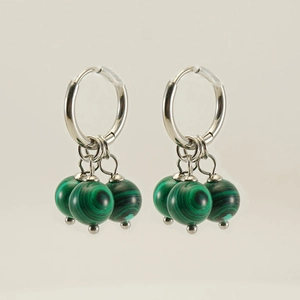 Détail de boucles d'oreilles argentées avec trois perles de malachite verte sur fond blanc