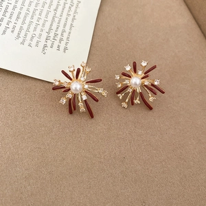 Detailed view of fireworks-inspired earrings with dark red glaze and central pearl