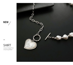 Detailed macro view of heart pendant necklace with irregular pearls and silver chain