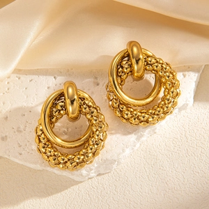 Close-up of golden titanium steel double hoop earrings on silk fabric and stone