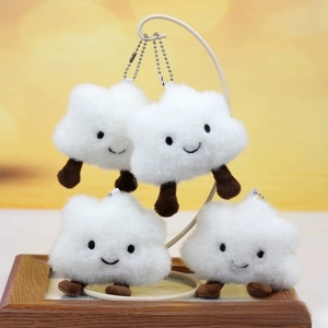 Detail of four cute plush white cloud keychains with embroidered smiles on a display stand