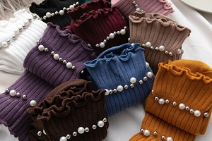 Detail of colorful knitted mid-tube socks with ruffled edges and pearl rivet decorations