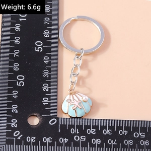Detail of seashell keychain with starfish and pearl accent next to a size measuring ruler
