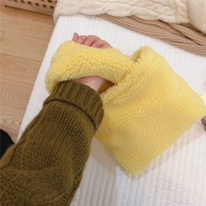 Détail de la texture en fausse fourrure jaune douce sur le mini sac à main en peluche