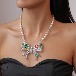 Elegant pearl necklace featuring a colorful gemstone bow pendant worn by a female model