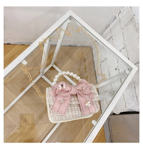 Detail of pink tweed girl crossbody bag featuring pearl handle and large ribbon bow