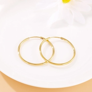 Classic minimalist gold hoop earrings displayed on white ceramic plate with soft floral decor