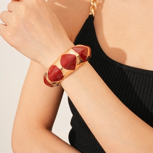 Detail of vintage gold textured cuff bracelet with red enamel inlay on a woman's wrist