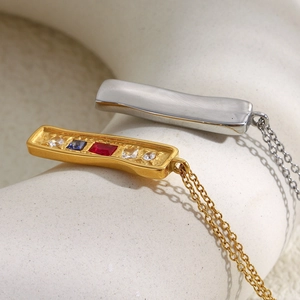 Close-up of gold and silver rectangular pendant necklaces with colorful zircon stones