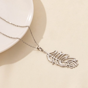 Macro detail of leaf feather pendant showing intricate hollow texture on a steel chain