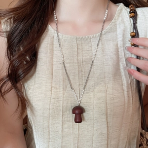 Dettaglio ravvicinato della collana con ciondolo a fungo marrone e perline in argento