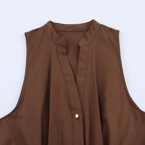 Detailed view of the V-neckline and gold button on a dark brown sleeveless dress