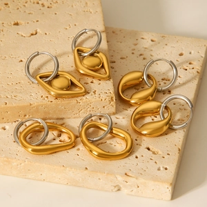 Minimalist two-tone geometric stainless steel earrings displayed on a rustic stone base