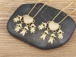 Dettaglio di ciondoli a cuore placcati oro 18k con figure di bambini su ciottoli neri