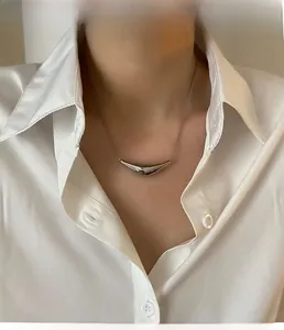 Gros plan d'un pendentif incurvé argenté minimaliste avec une chaîne serpent fine