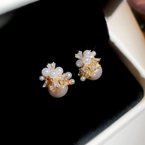 Macro view of vintage pearl and zircon cluster earrings with gold setting details
