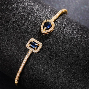 Elegant gold open cuff bracelet with blue drop and rectangle stones and micro zircons