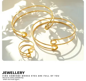 Artistic set of gold safety pin bracelets and ring on a white surface with shadows